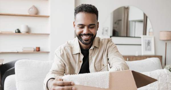 Black man smiling while opening a package