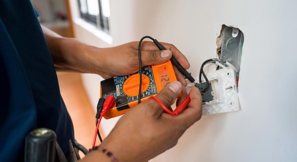Electrician fixing an electrical outlet and measuring the voltage
