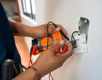 Electrician fixing an electrical outlet and measuring the voltage