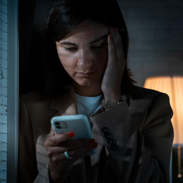 Scared women looking at mobile phone in the dark