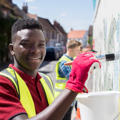 Young black boy painting a fence for work experience