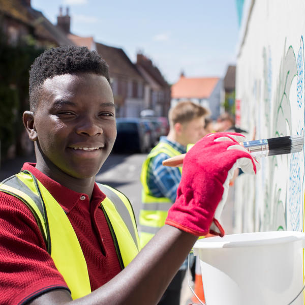 Young black boy painting a fence for work experience