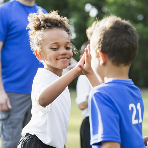 Kids high-fiving at football - stock