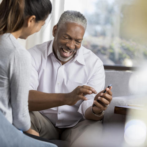 Older black man being shown how to use his phone