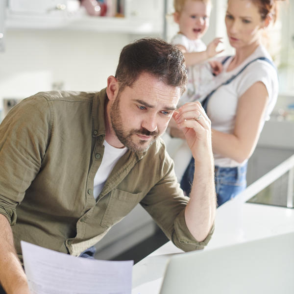 Young white family sat in the kitchen reading a document looking nervous