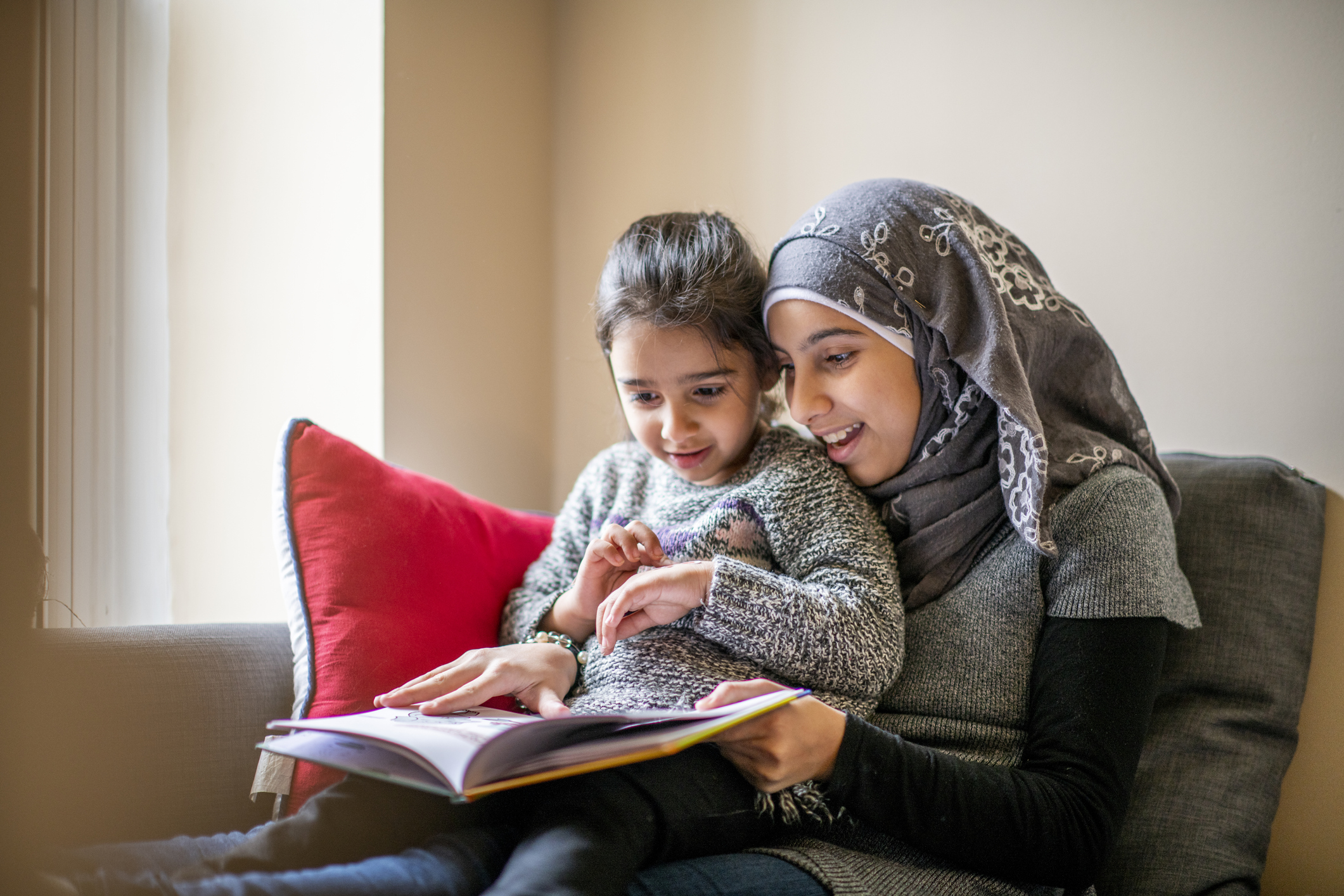 Muslim mother and her child reading a book