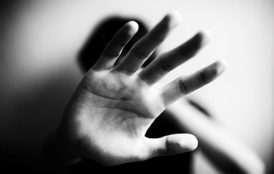 A black and white photo of a hand being held up to the camera gesturing to stop