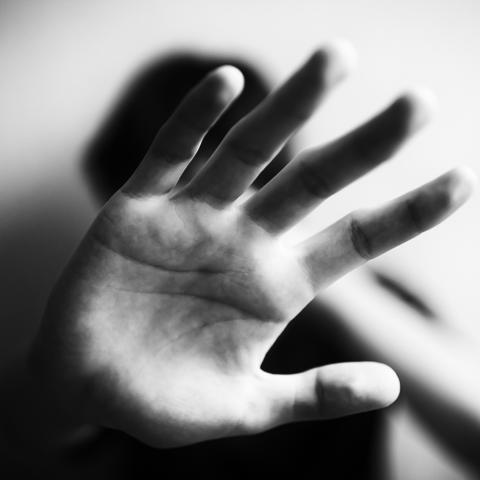A black and white photo of a hand being held up to the camera gesturing to stop