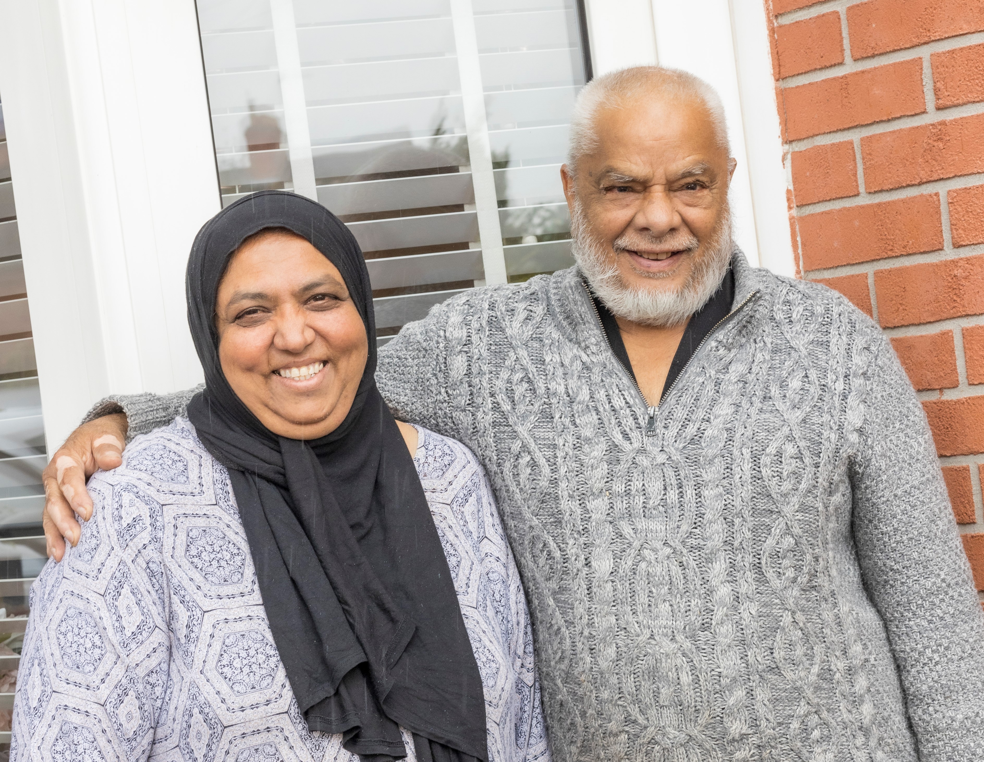 Older Muslim couple outside their home