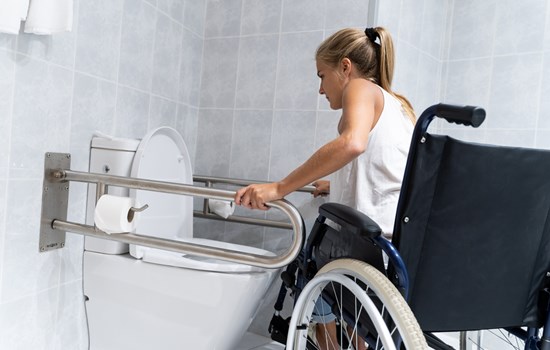Women in wheelchair using grab rails - stock
