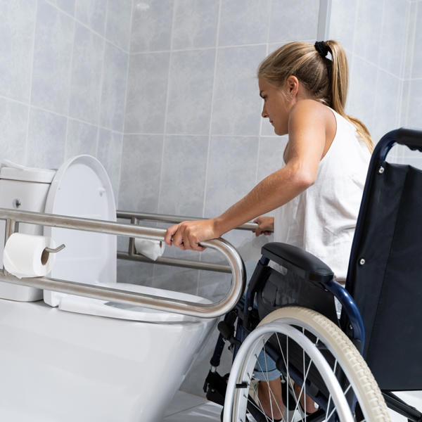 Women in wheelchair using grab rails - stock
