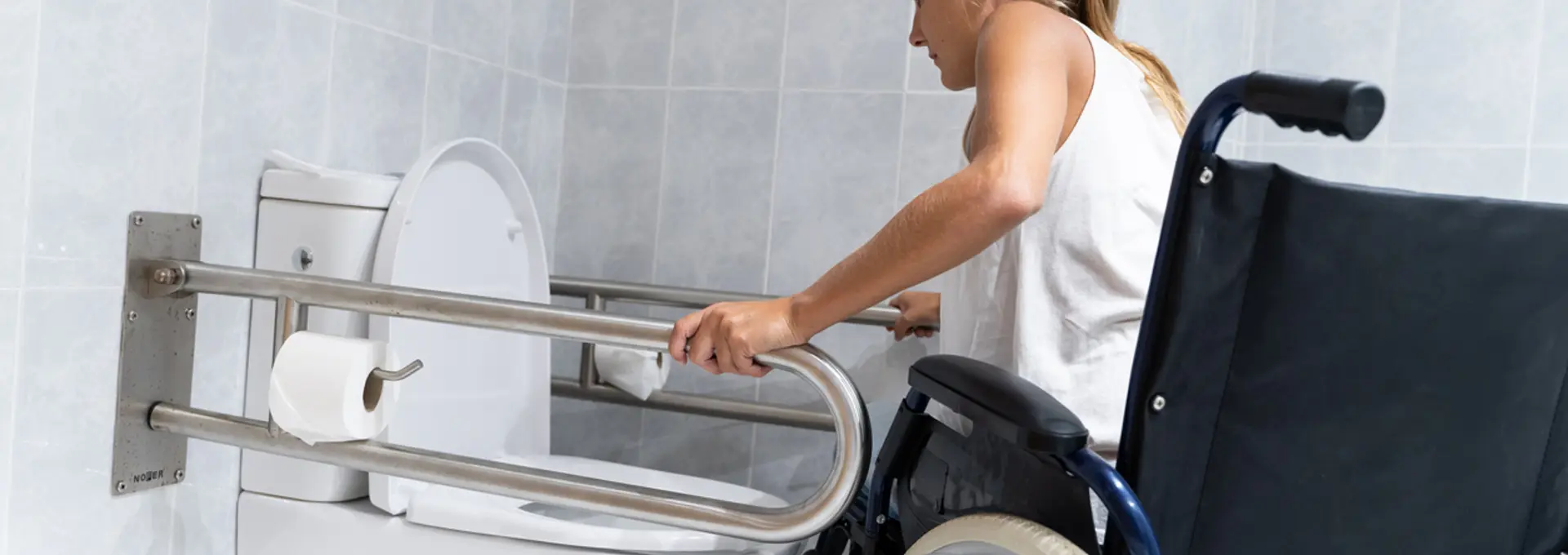 Women in wheelchair using grab rails to use a toilet
