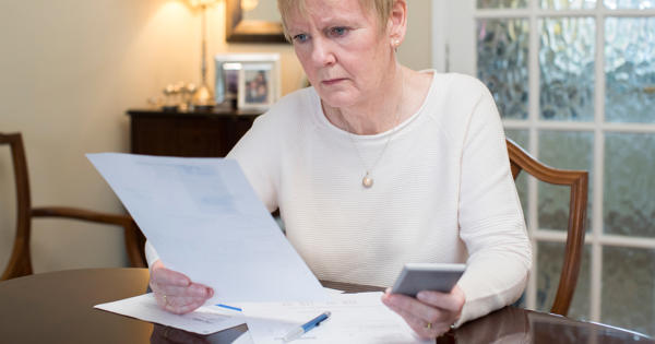 Older lady looking worried at paperwork - stock