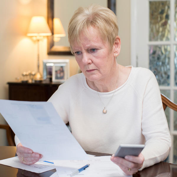 Older lady looking worried at paperwork - stock