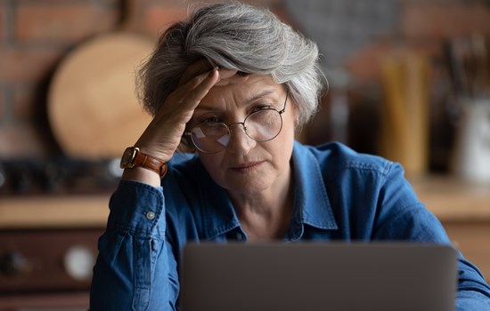 Older lady looking worried on laptop - stock