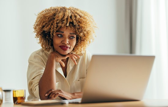 Black woman smiling at laptop - stock