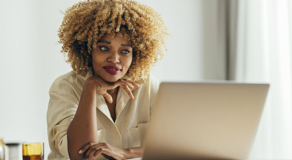 Black woman smiling at laptop - stock