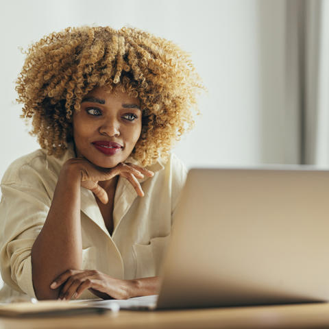 Black woman smiling at laptop - stock