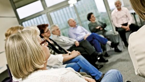 A group of people sat at a community meeting listening