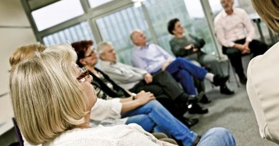 A group of people sat at a community meeting listening A group of people sat at a community meeting listening