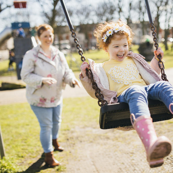 Mother pushing child on swing