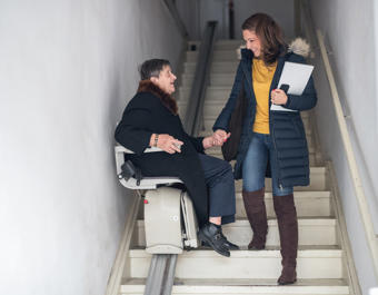Younger women helps an older women use a stairlift