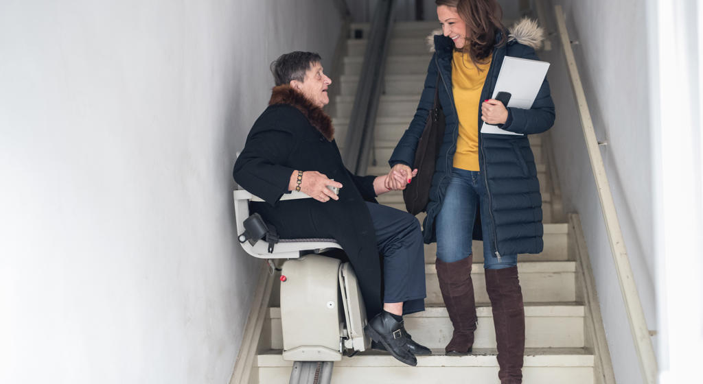 Younger women helps an older women use a stairlift