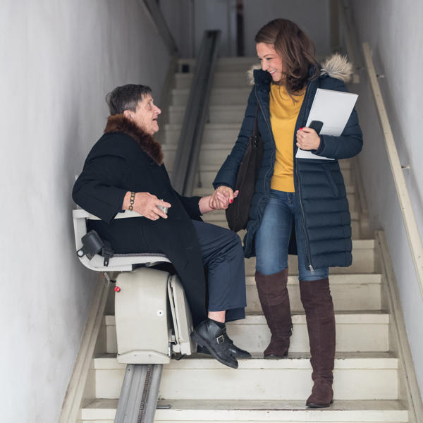 Younger women helps an older women use a stairlift