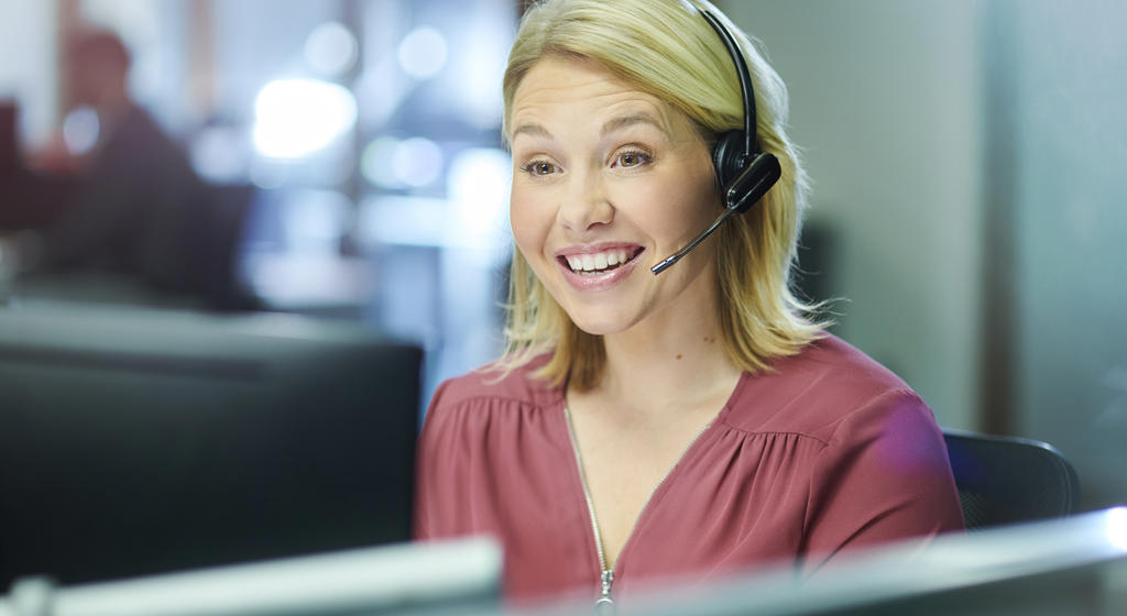 Female call centre worker wearing a headset and smiling