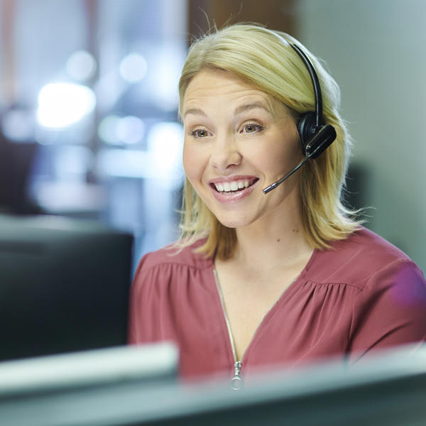 Female call centre worker wearing a headset and smiling