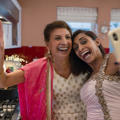Two Asian women taking a selfie while cooking. Both women are wearing saris.