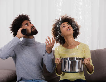 Woman Using Utensil For Collecting Water Leaking From Ceiling