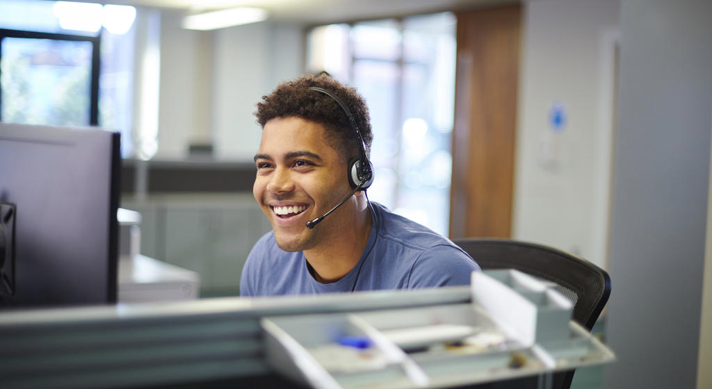 Male call centre worker wearing a headset smiling