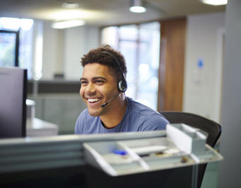 Male call centre worker wearing a headset smiling