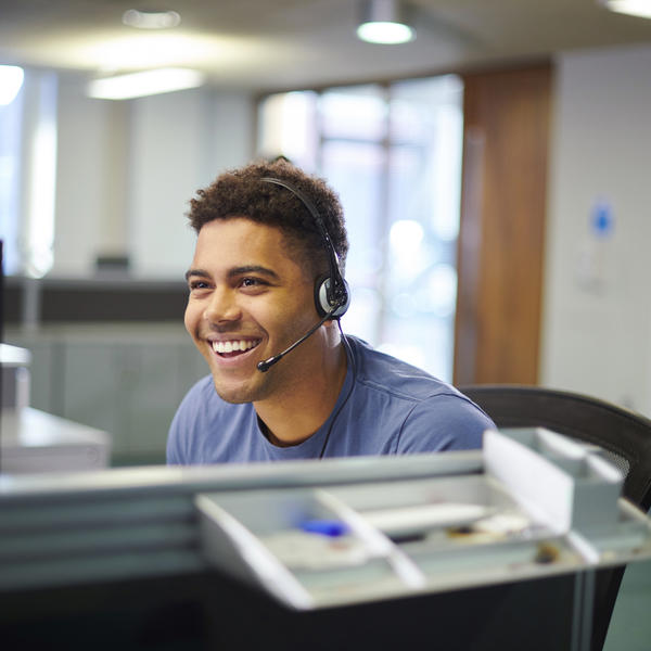 Male call centre worker wearing a headset smiling