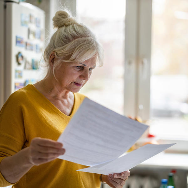 White women in yellow top reading paperwork looking confused