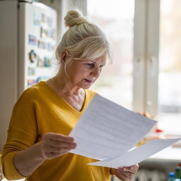 White women in yellow top reading paperwork looking confused