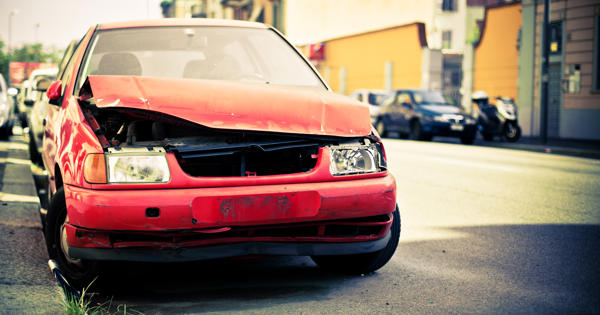 Red abandoned and broken car on the side of the road