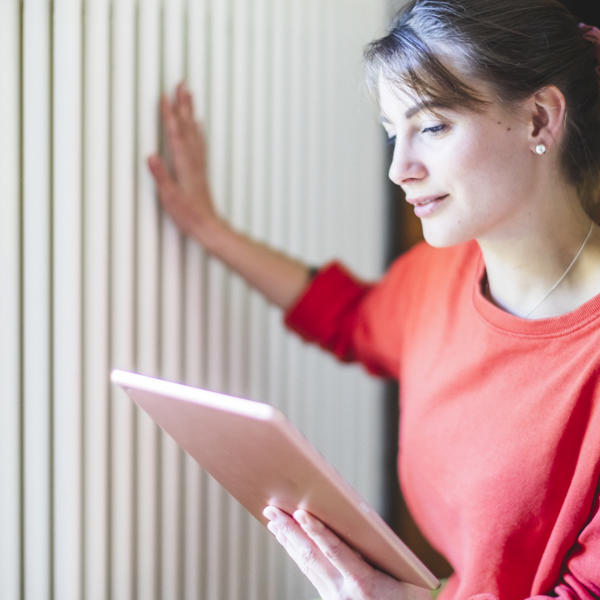 Young woman touching radiators in living room to check it's working