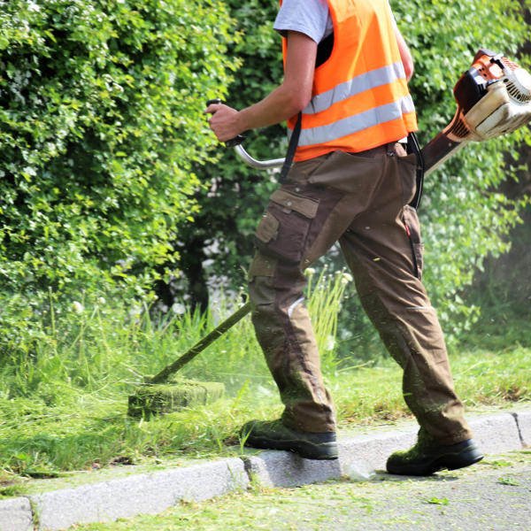 Workman using a strimmer to cut the grass