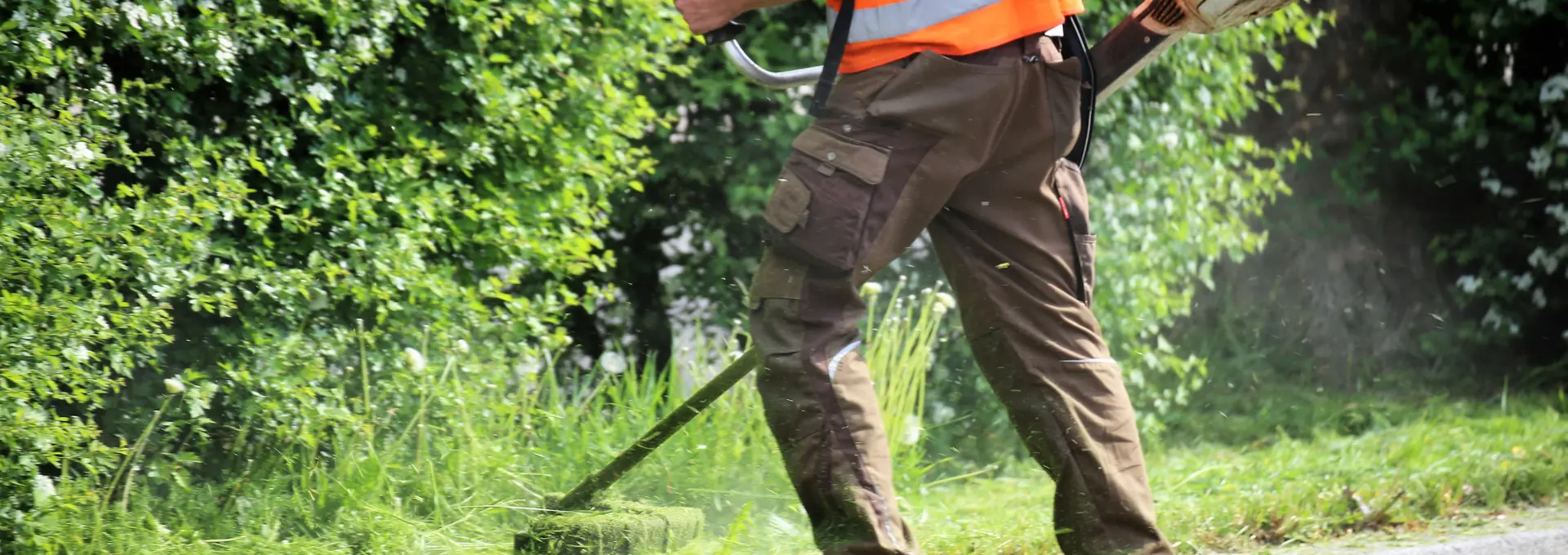 Workman using a strimmer to cut the grass