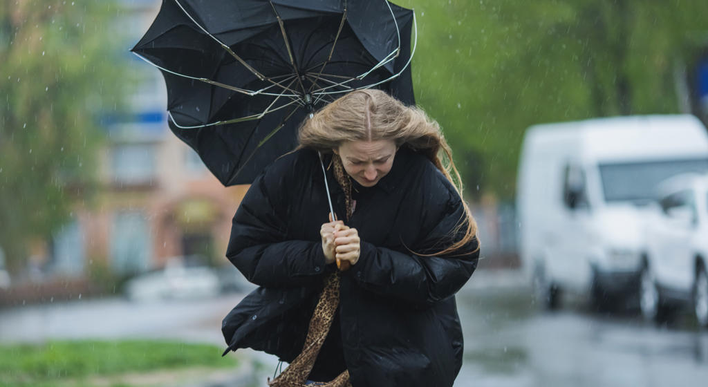 Blonde woman under umbrella. Storm weather. Torrential rain