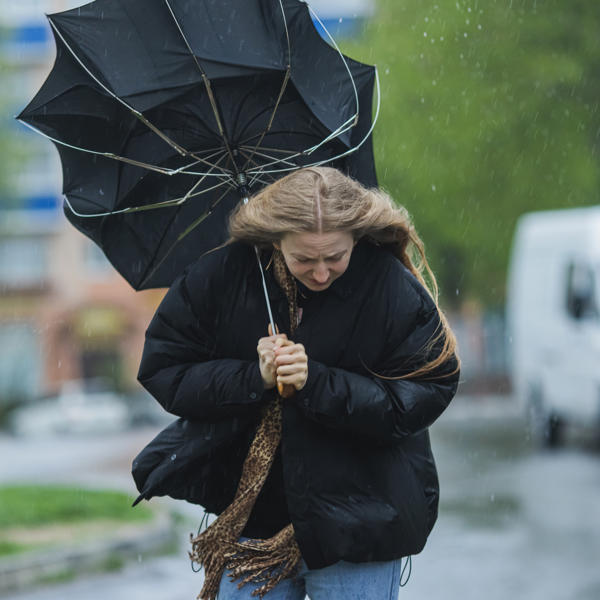 Blonde woman under umbrella. Storm weather. Torrential rain