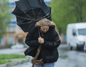 Blonde woman under umbrella. Storm weather. Torrential rain