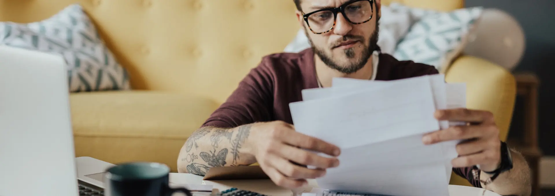 Young man sat on floor with a laptop checking paperwork