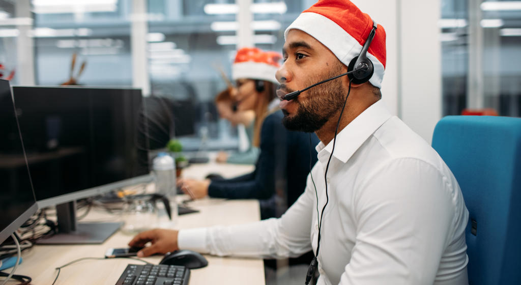 Man in santa hat answering the phones in customer call centre.