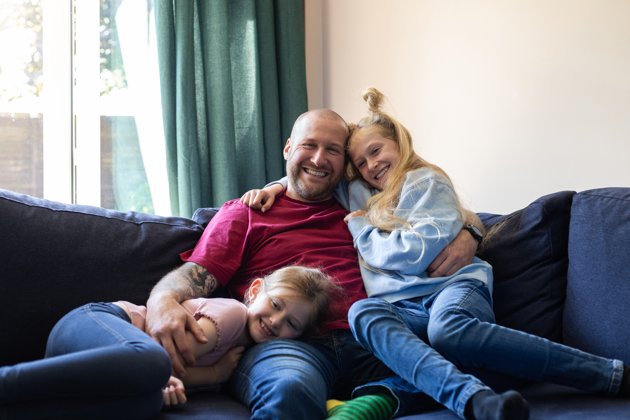 Dad sat on sofa with two young daughters