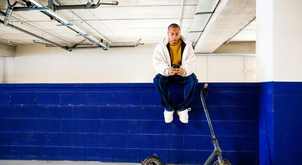 Man sat on a wall with an escooter in front of him