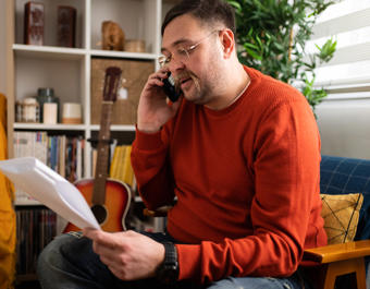 Man On Phone Looking Confused While Holding Paperwork