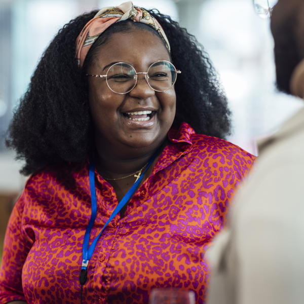 Black women smiling in the office while at work speaking to colleagues